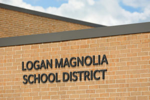 A building sign reading "Logan Magnolis School District" on a brick facade of a school building.